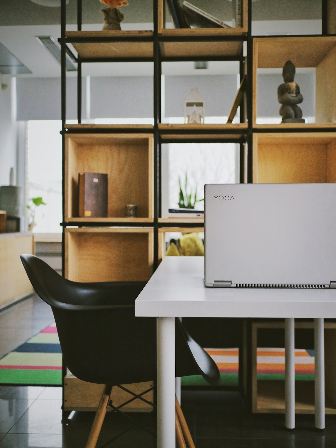 Silver laptop closed on a desk beside a black chair.